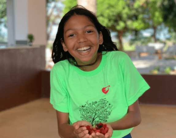 Menina com frutas vermelhas em sua mão